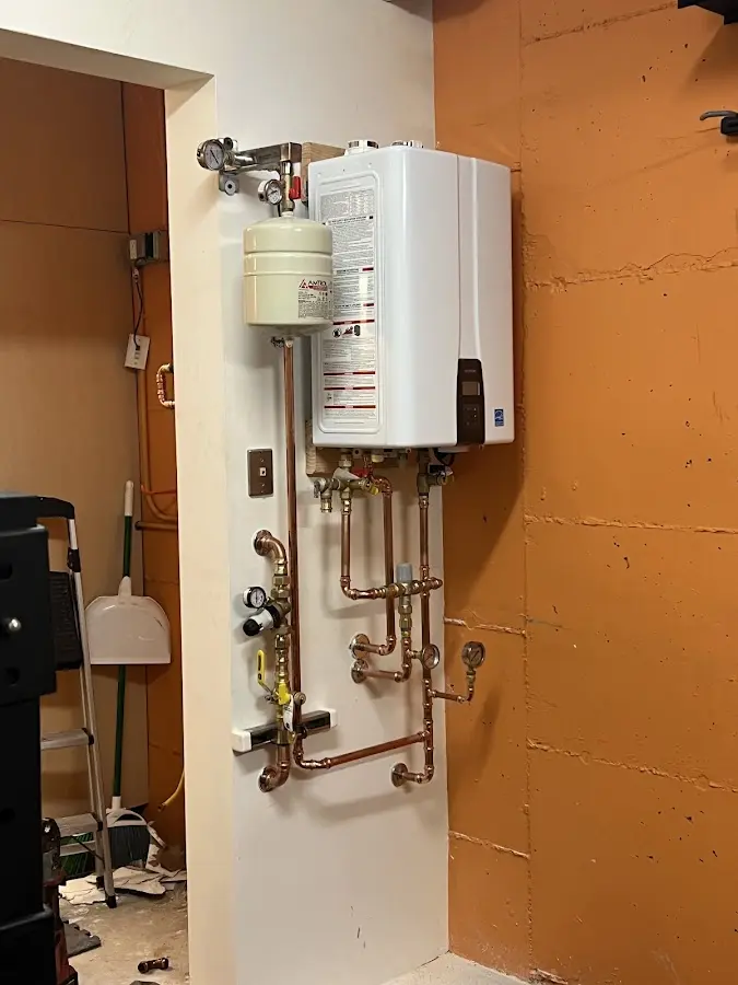 Plumbing technician inspecting water heater connections in Upper